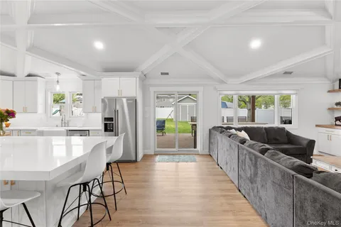 a living room with stainless steel appliances kitchen island furniture and a large window