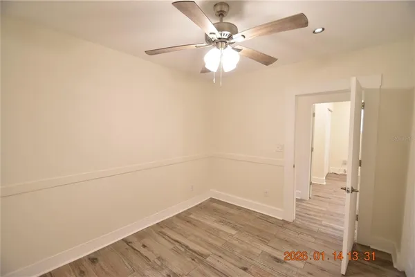 wooden floor in an empty room with a chandelier fan