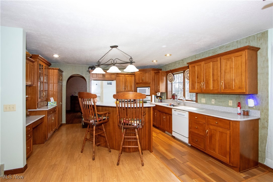 11079 Colwill Road Gambier, OH 43022 - Photo 12 of 41 Kitchen with light wood-style flooring, arched walkways, brown cabinetry, and white appliances