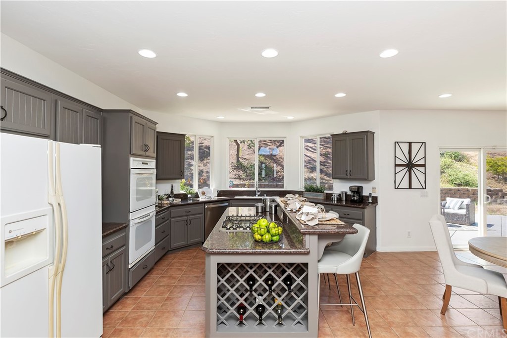 33425 Monte Verde Temecula, CA 92592 - Photo 27 of 68 a kitchen with stainless steel appliances granite countertop a refrigerator a stove a sink a dining table and chairs with wooden floor