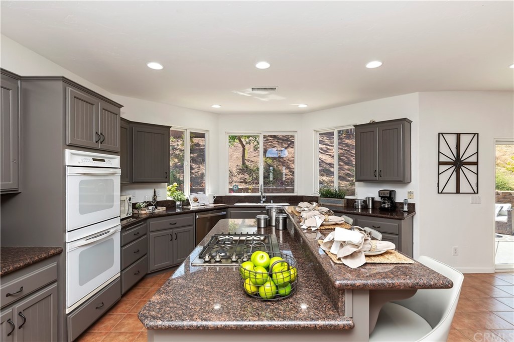 33425 Monte Verde Temecula, CA 92592 - Photo 30 of 68 a kitchen with stainless steel appliances granite countertop a stove top oven a sink a dining table and chairs with wooden floor