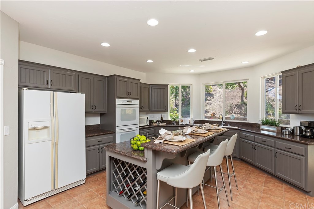 33425 Monte Verde Temecula, CA 92592 - Photo 59 of 68 a kitchen with stainless steel appliances granite countertop a refrigerator a sink a stove a dining table and chairs