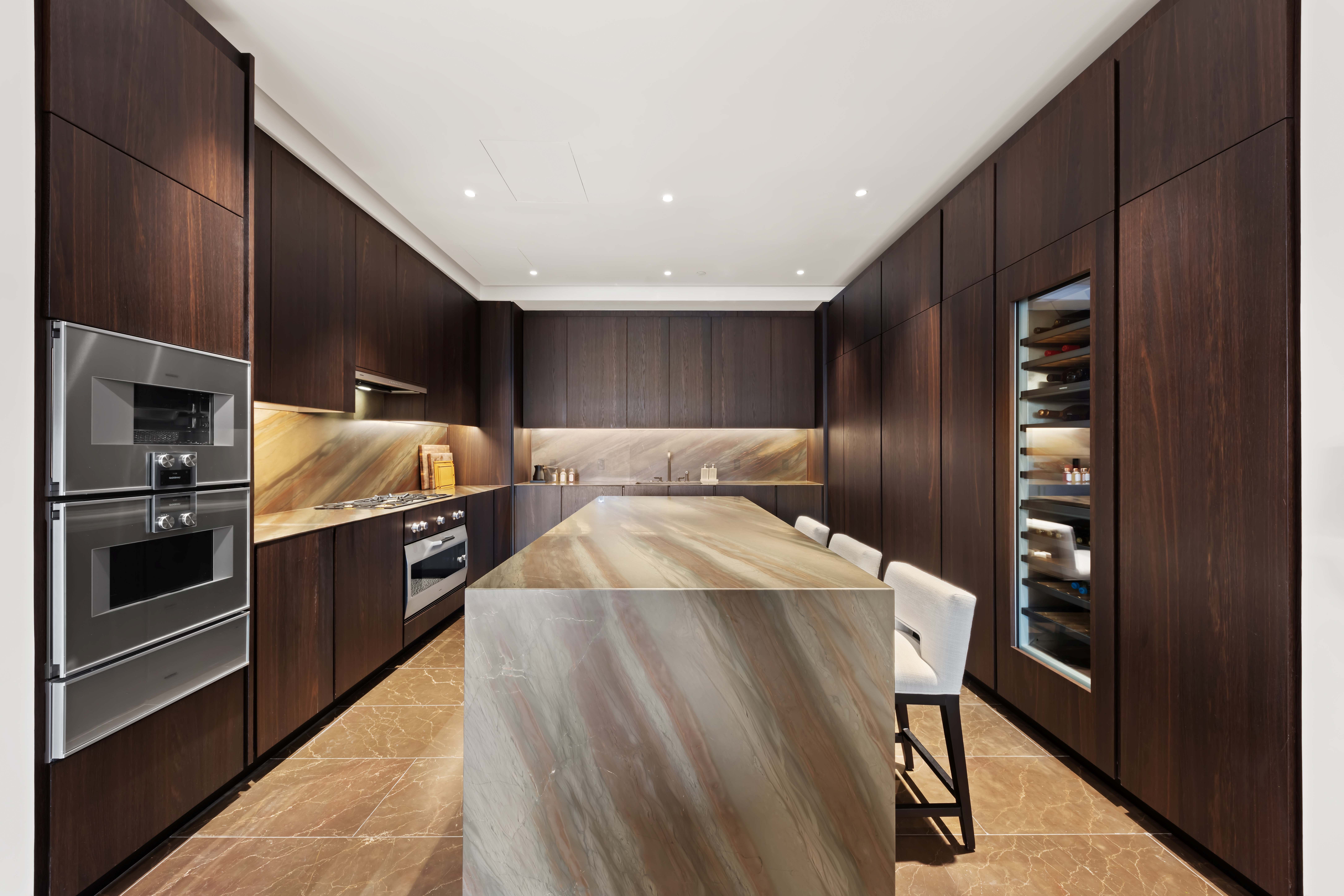 730 5th Avenue, Unit 18B Manhattan, NY 10019 - Photo 5 of 10 a kitchen with stainless steel appliances kitchen island granite countertop a refrigerator and a stove top oven