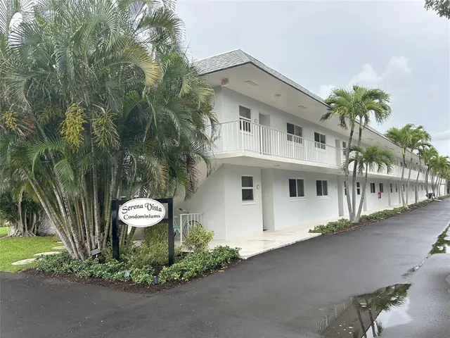 a view of a white house with a small yard and plants