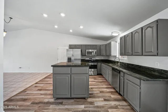 a living room with stainless steel appliances furniture a refrigerator and a view of kitchen