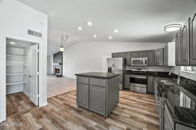 a kitchen with stainless steel appliances kitchen island granite countertop a stove and a sink