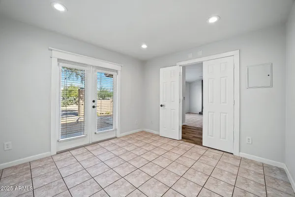 a view of an empty room with window and chandelier fan