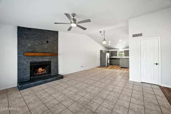 a view of an empty room with window and chandelier fan