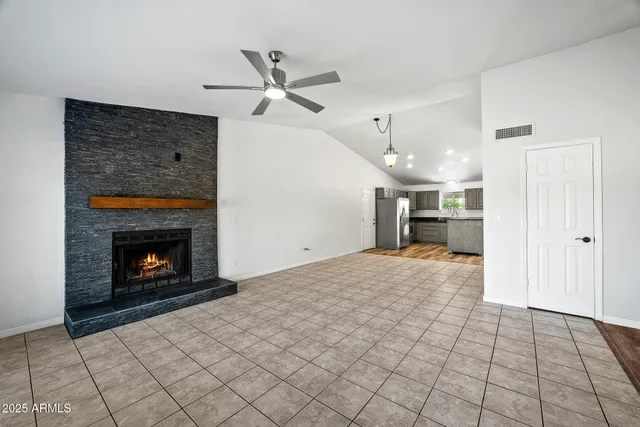 a view of an empty room with window and chandelier fan