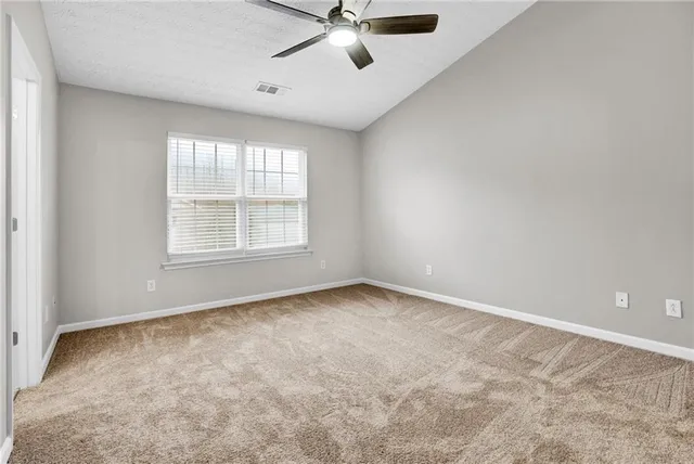 an empty room with ceiling fan and windows