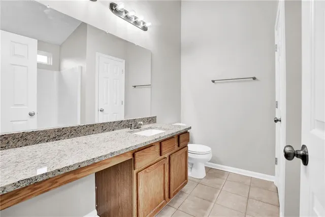 a bathroom with a granite countertop sink a toilet and a shower