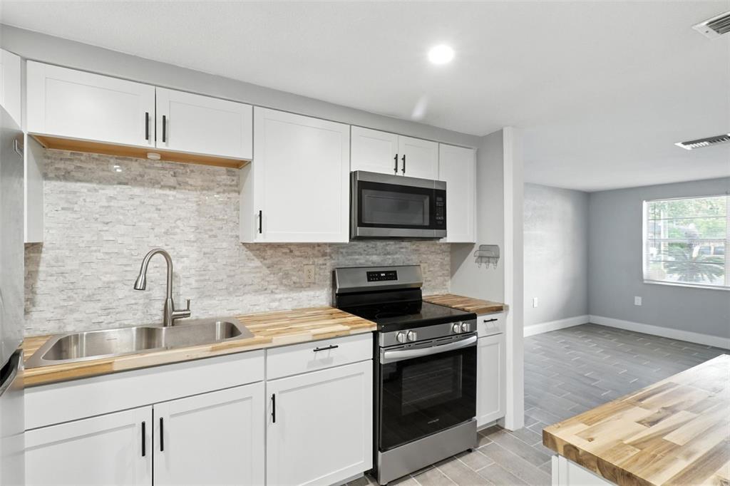 8035 Gulf Way Hudson, FL 34667 - Photo 11 of 26 a kitchen with stainless steel appliances granite countertop a sink a stove a microwave and cabinets