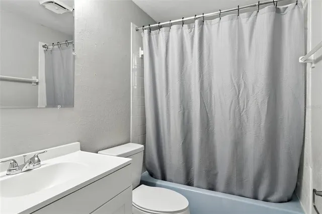 a bathroom with a sink a toilet and shower curtain