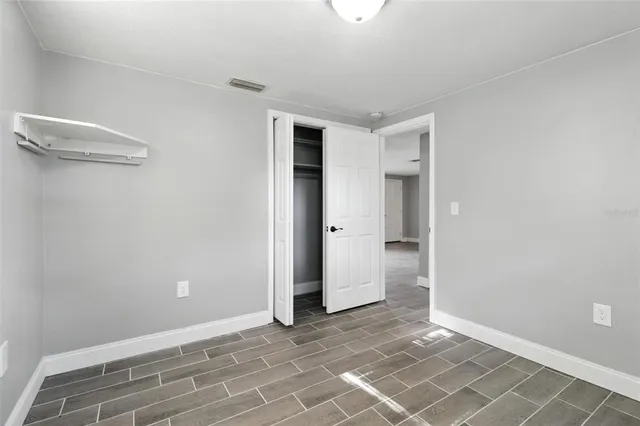 a view of an empty room with closet and a window