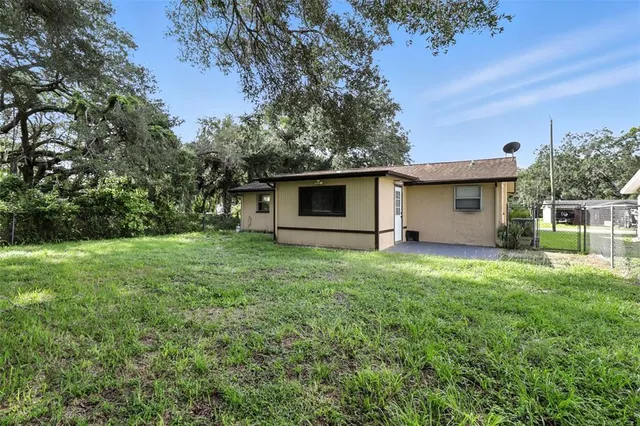 a view of a backyard with plants and large tree
