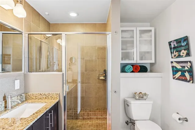 a bathroom with a granite countertop sink toilet a shower and a mirror