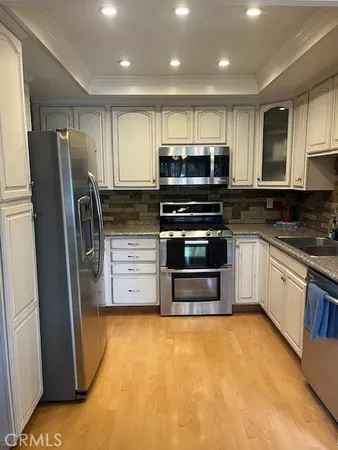 a kitchen with stainless steel appliances granite countertop a refrigerator a stove and a sink