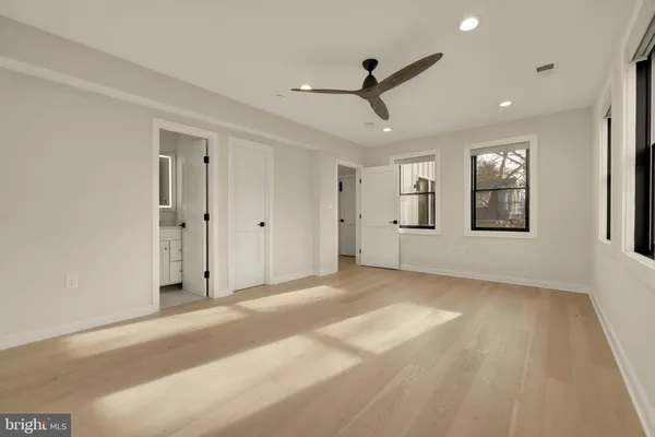 a view of a livingroom with a ceiling fan & windows