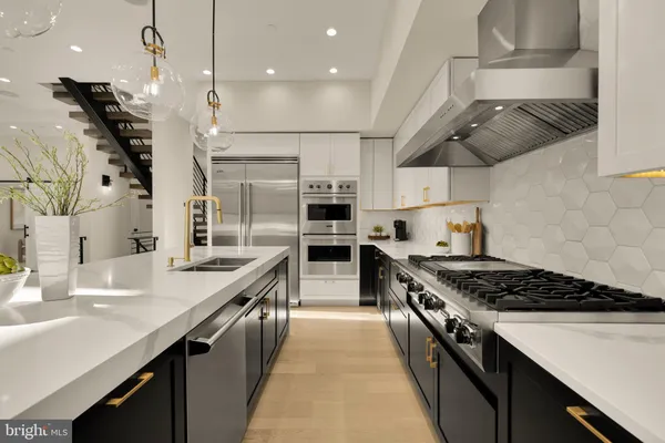 a kitchen with stainless steel appliances granite countertop a stove a sink dishwasher and a refrigerator with wooden floor