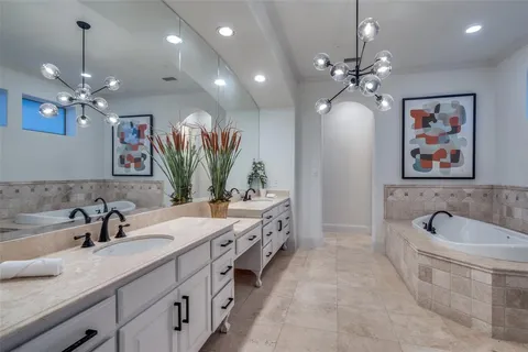 a spacious bathroom with a double vanity sink a large mirror and a bathtub