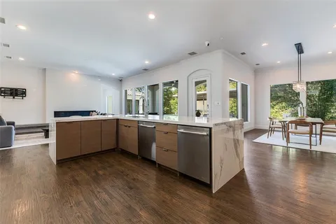a large white kitchen with wooden floors and stainless steel appliances