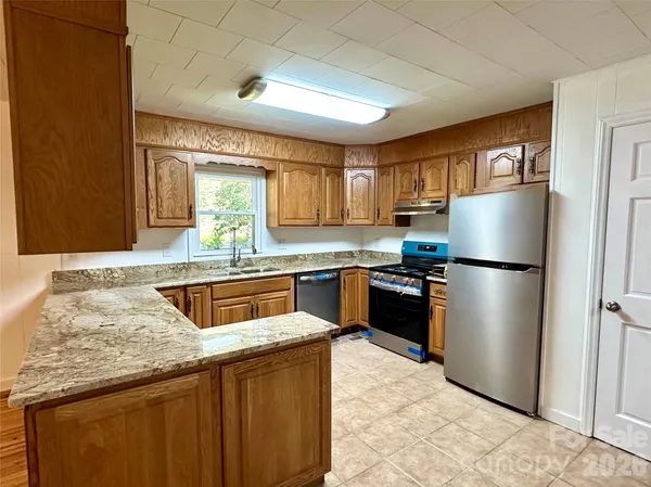 a kitchen with kitchen island granite countertop a sink stainless steel appliances and cabinets