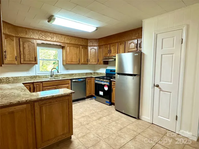 a kitchen with stainless steel appliances granite countertop a refrigerator a sink a stove a refrigerator and white cabinets