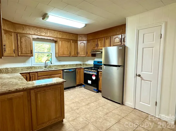 a kitchen with stainless steel appliances granite countertop a refrigerator a sink a stove a refrigerator and white cabinets