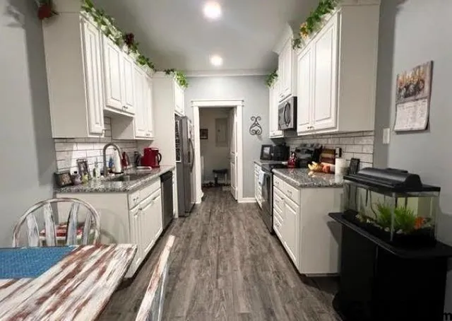 a kitchen with granite countertop a stove a sink dishwasher and cabinets with wooden floor
