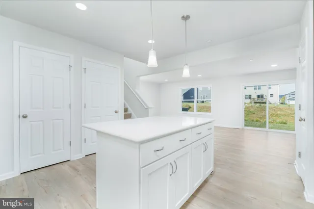 a view of a kitchen with kitchen island a sink wooden floor and living room view