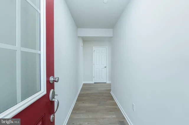 a view of a hallway with wooden floor and a bathroom