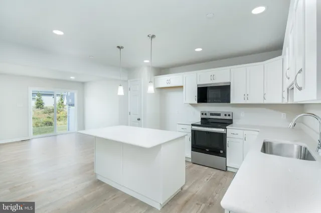 a large kitchen with stainless steel appliances kitchen island granite countertop a stove a sink dishwasher and a microwave with wooden floor