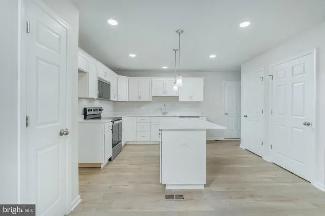 a large kitchen with stainless steel appliances granite countertop a sink a stove a refrigerator and white cabinets