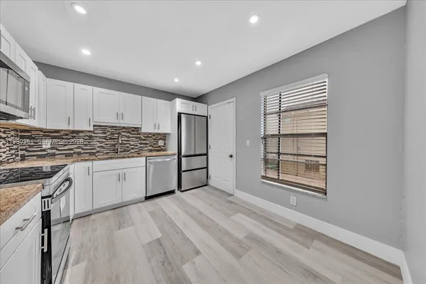 a kitchen with white cabinets and wooden floor