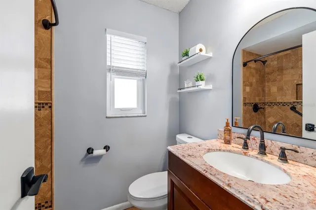 a bathroom with a granite countertop sink toilet a mirror and shower
