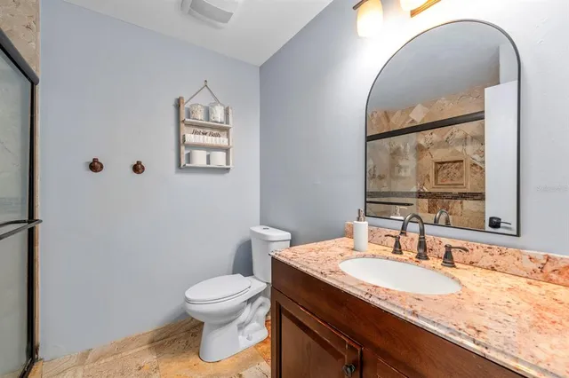 a bathroom with a granite countertop sink a toilet and a mirror