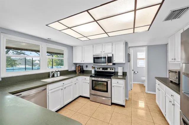 a kitchen with stainless steel appliances granite countertop a sink a stove top oven a refrigerator with white cabinets and dishwasher