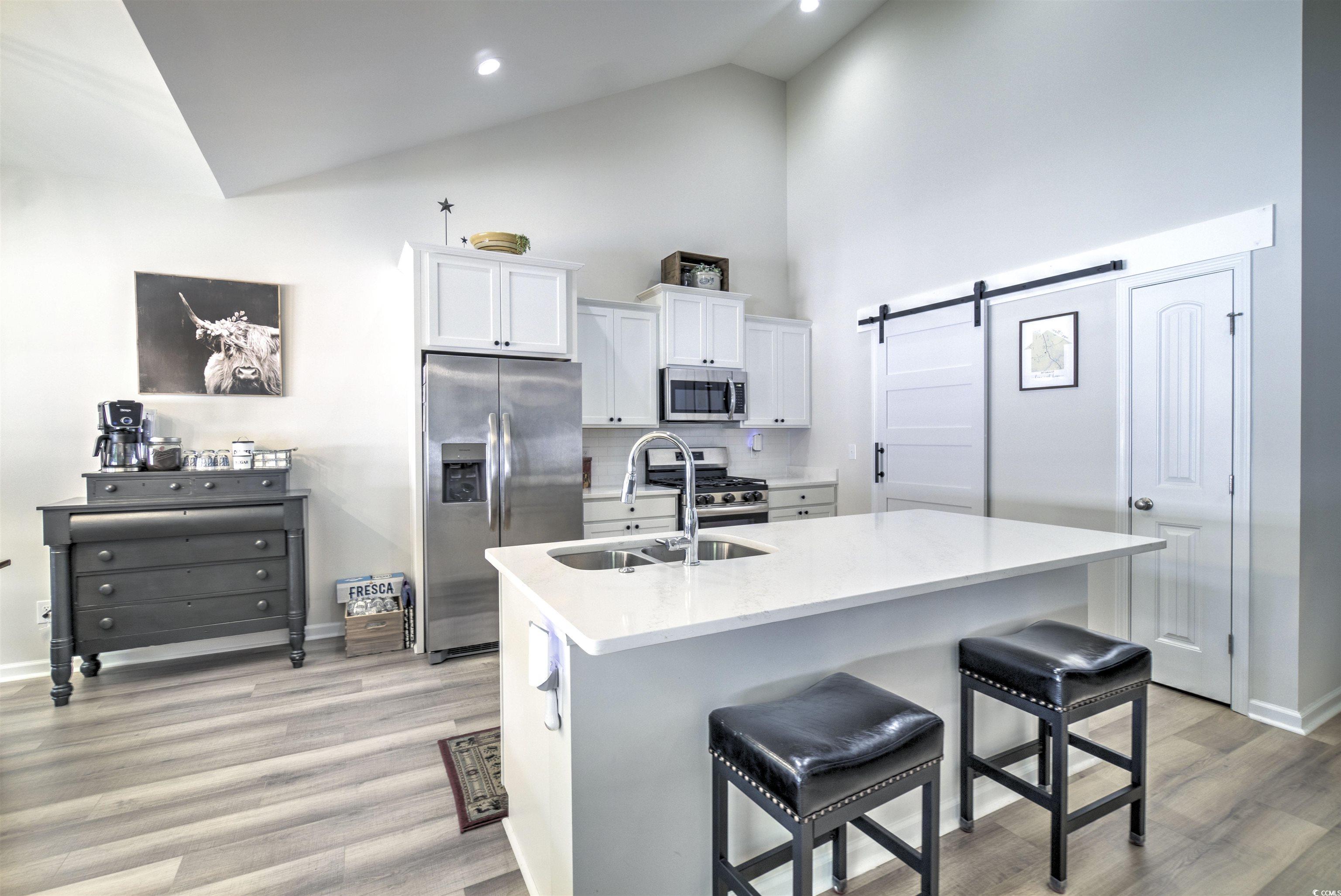 267 Lakota Loop Longs, SC 29568 - Photo 12 of 23 Kitchen with a barn door, white cabinetry, appliances with stainless steel finishes, high vaulted ceiling, and a kitchen bar