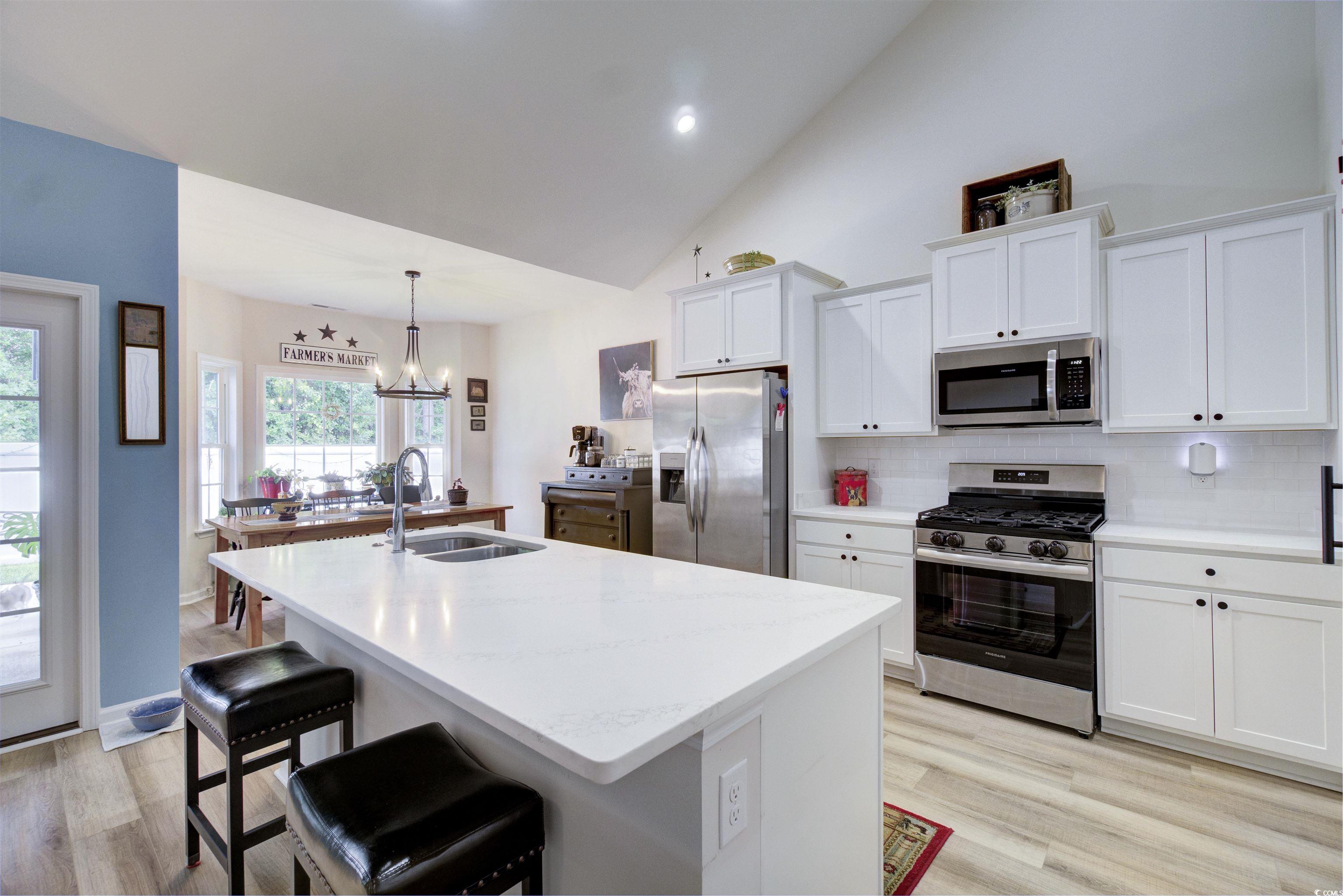 267 Lakota Loop Longs, SC 29568 - Photo 16 of 23 Kitchen with white cabinetry, stainless steel appliances, tasteful backsplash, a kitchen bar, and light wood-type flooring