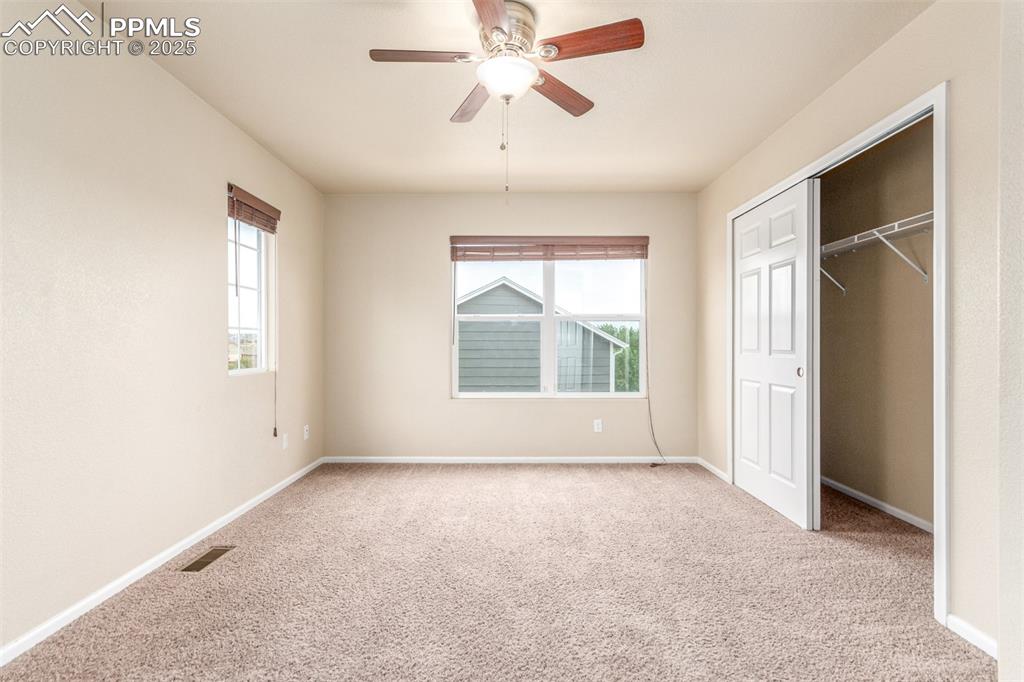 7750 Dutch Loop Colorado Springs, CO 80925 - Photo 19 of 50 an empty room with chandelier fan and windows