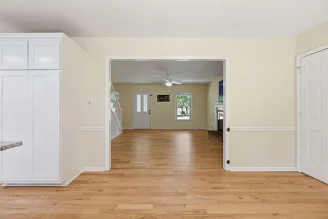a view of a livingroom with wooden floor and a refrigerator