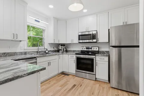 a kitchen with granite countertop a refrigerator stove a sink and a microwave
