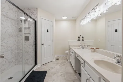 a spacious bathroom with a double vanity sink mirror and shower