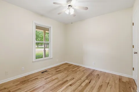 an empty room with a window and wooden floor