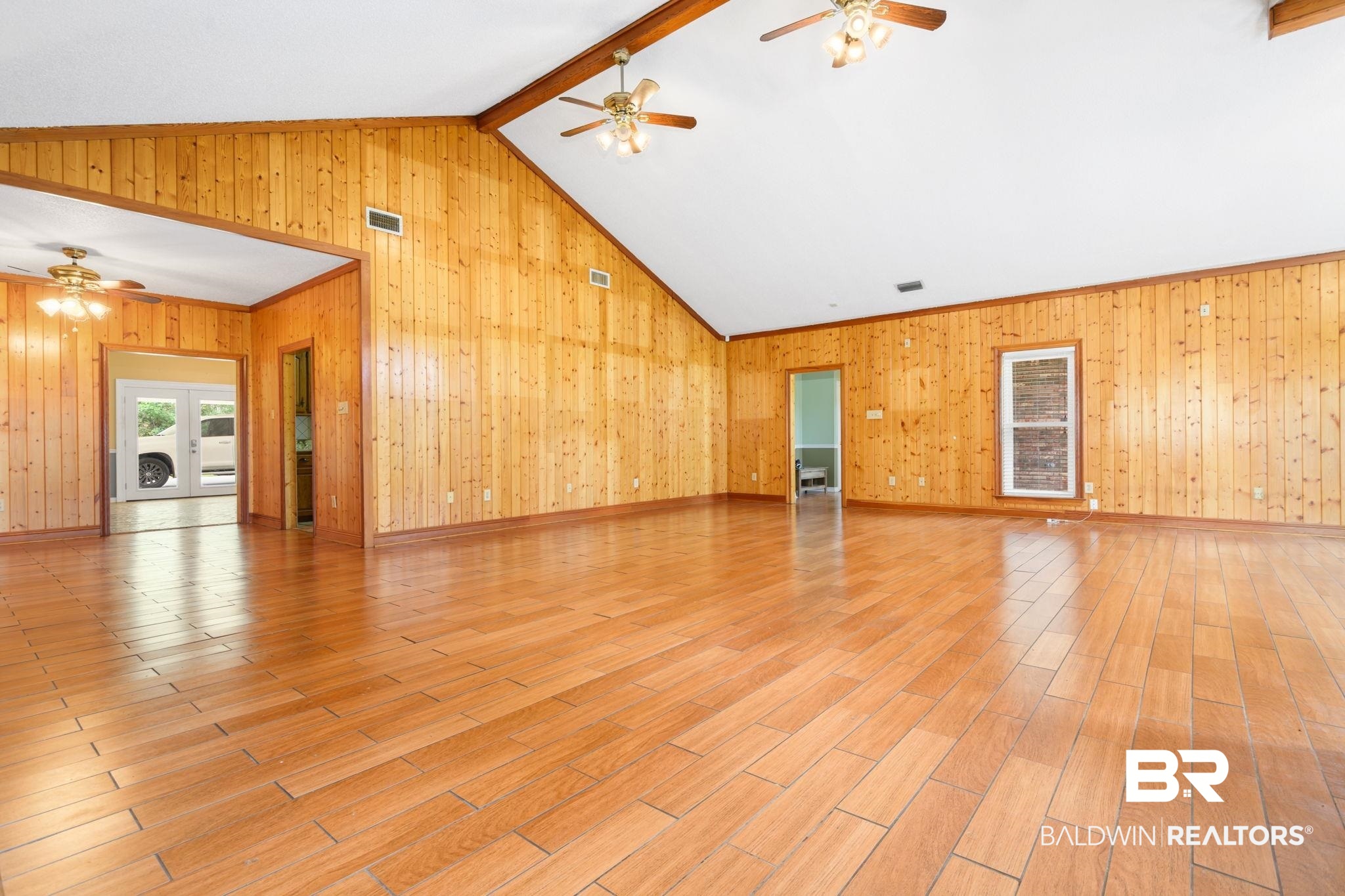 7540 2 Mile Road Irvington, AL 36544 - Photo 15 of 82 Spacious room featuring wood-finish flooring, wood paneling, and a vaulted ceiling with exposed beams