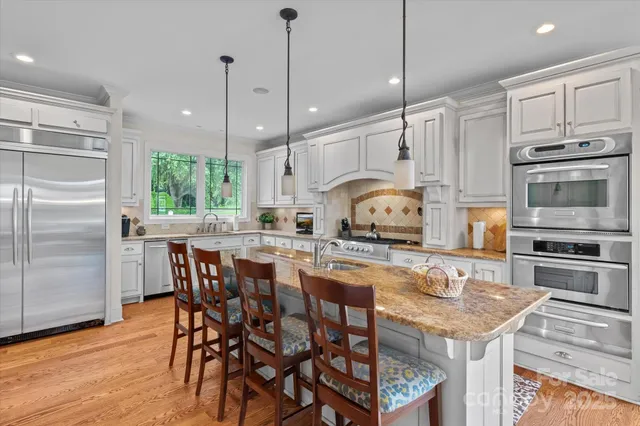a kitchen with stainless steel appliances granite countertop a stove a refrigerator a kitchen island a table and chairs