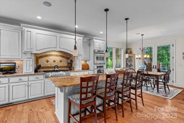 a kitchen with stainless steel appliances granite countertop a table chairs sink and cabinets
