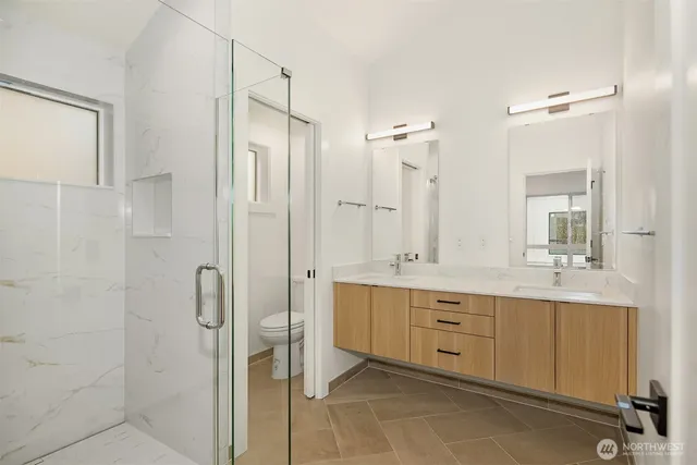 a spacious bathroom with a double vanity sink a large mirror and shower