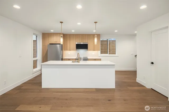 a view of kitchen with stainless steel appliances wooden floor