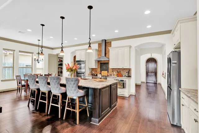 a large kitchen with stainless steel appliances granite countertop a stove and wooden floor